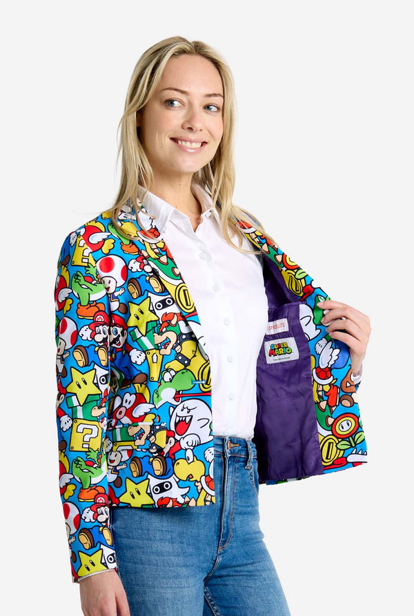 Woman wearing all-over print Super Mario blazer with iconic Super Mario characters. The base is light blue, but there is also yellow, red and white. Side view.