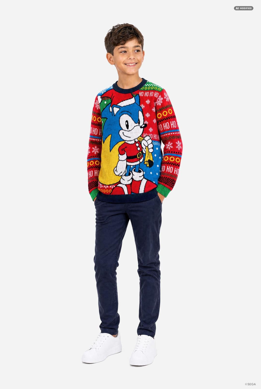 A young boy wearing a festive Christmas knit sweater featuring Sonic the Hedgehog, posed against a solid light gray background.