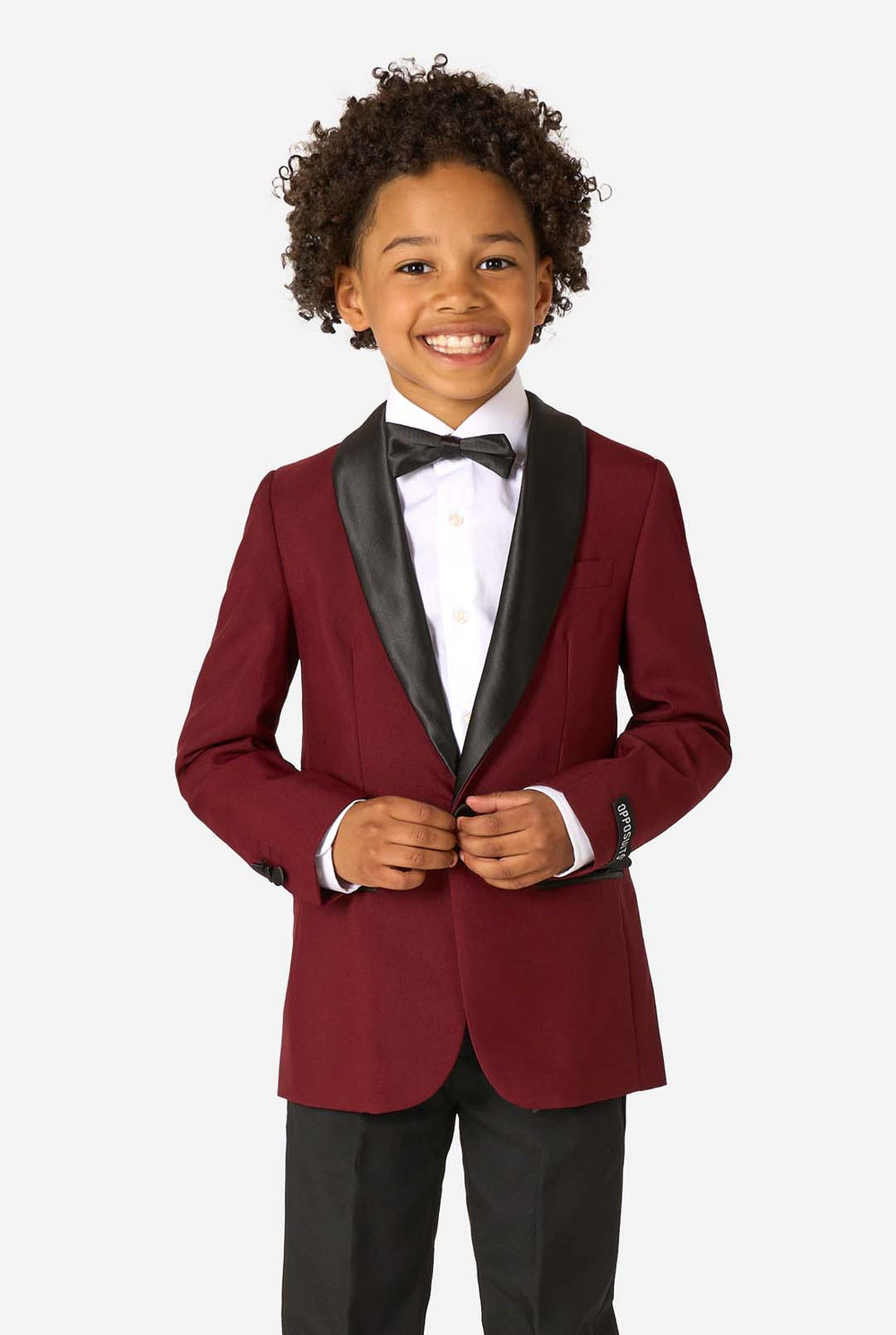 Child wearing a burgundy tuxedo with black lapels on a white background