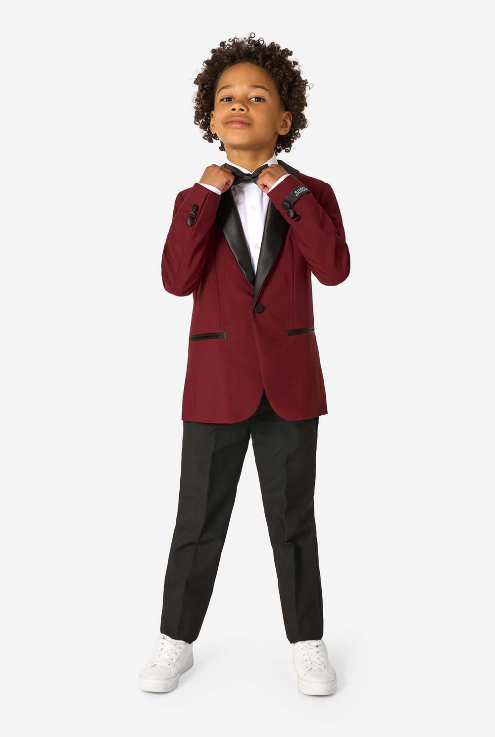 Child wearing a burgundy tuxedo with black lapels on a white background