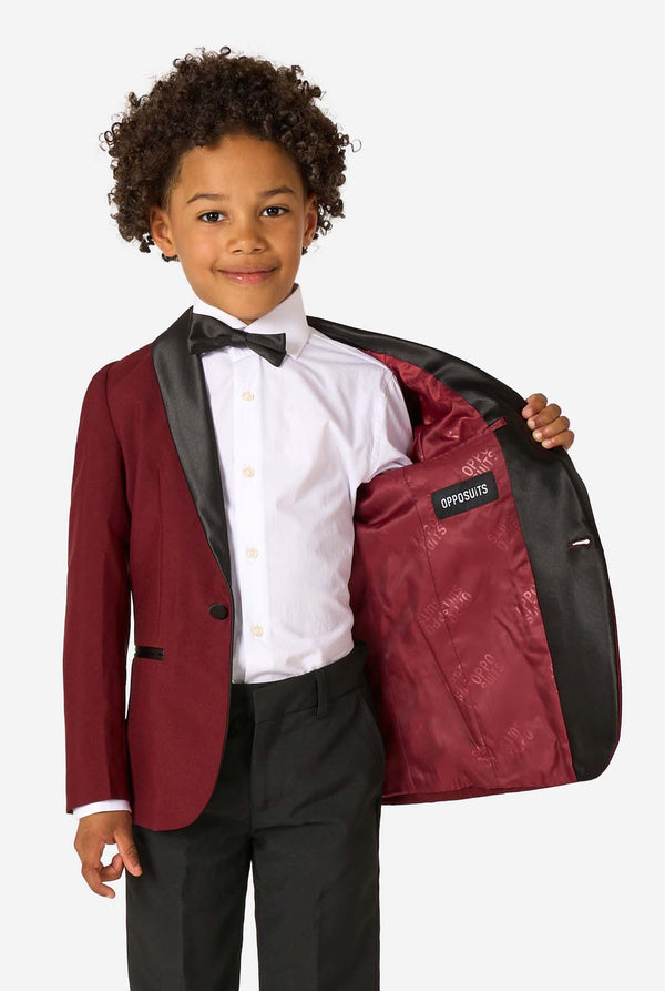 Child in a formal outfit holding a matching jacket with 'Opposites' text.
