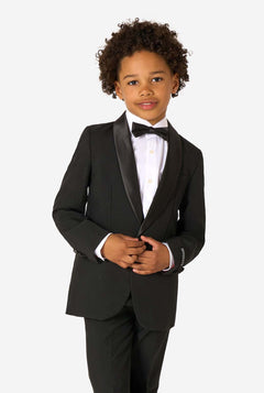 Child wearing a black tuxedo with a white shirt and black bow tie on a white background