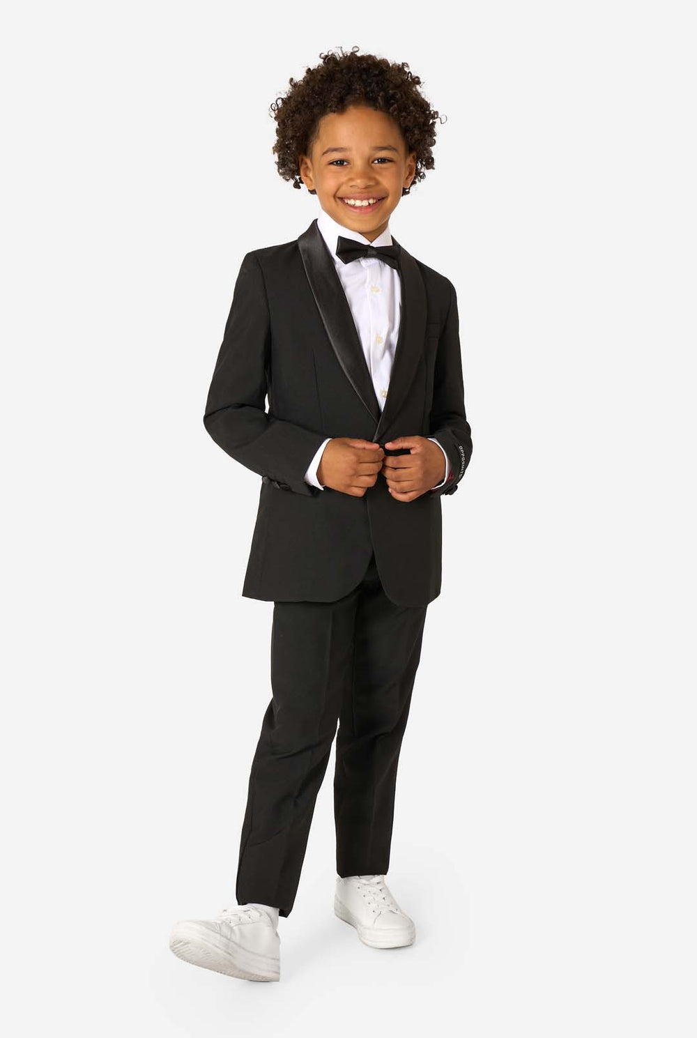 Child wearing a black tuxedo with a white shirt and black bow tie on a white background