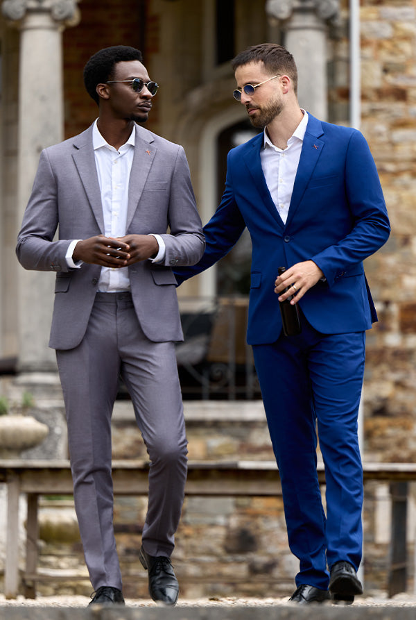 Image of two man next to each other. The man on the left is wearing a grey suit and the one on the rights is wearing a navy suit.