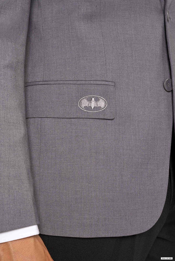 Close-up of a blazer pocket embroidered with a subtle grey Batman logo.