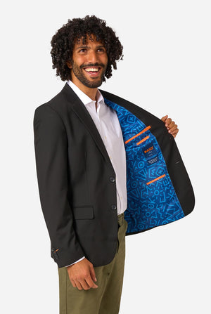 Man wearing a black blazer with a blue inner lining, standing against a light background