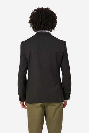 Person wearing a black blazer and beige pants on a light background