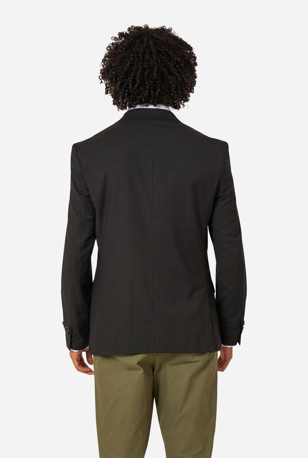 Person wearing a black blazer and beige pants on a light background