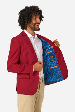 Man wearing a red blazer with a blue inner lining, standing against a white background