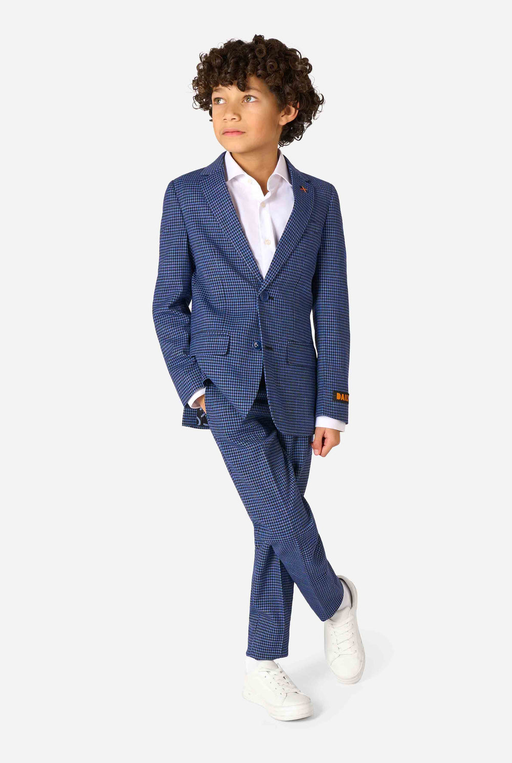 A boy wearing a navy and blue checkered suit with a white dress shirt. The suit has a modern fit with two buttons and flap pockets. He stands against a plain white background.