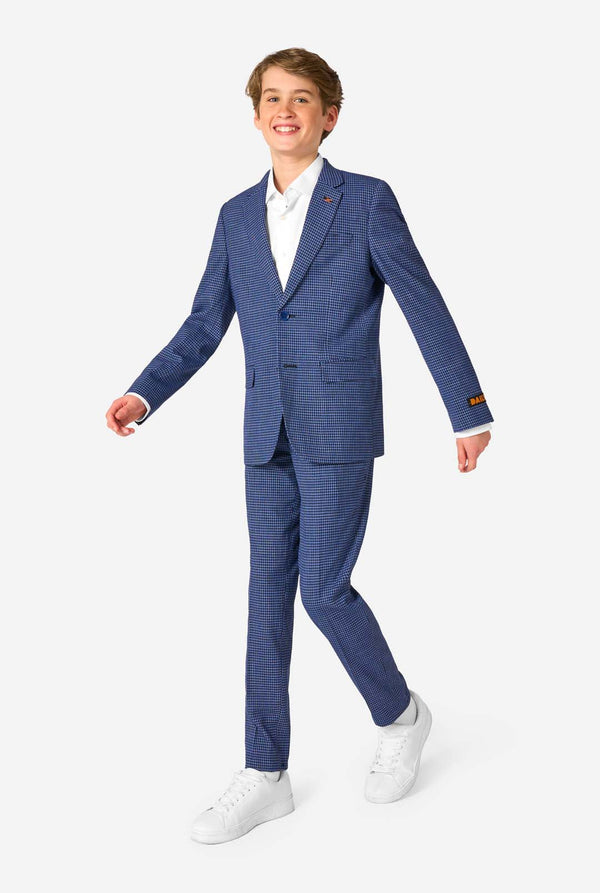 A teen boy wearing a navy and blue checkered suit with a white dress shirt. The suit has a modern fit with two buttons and flap pockets. He stands against a plain white background. Full body image