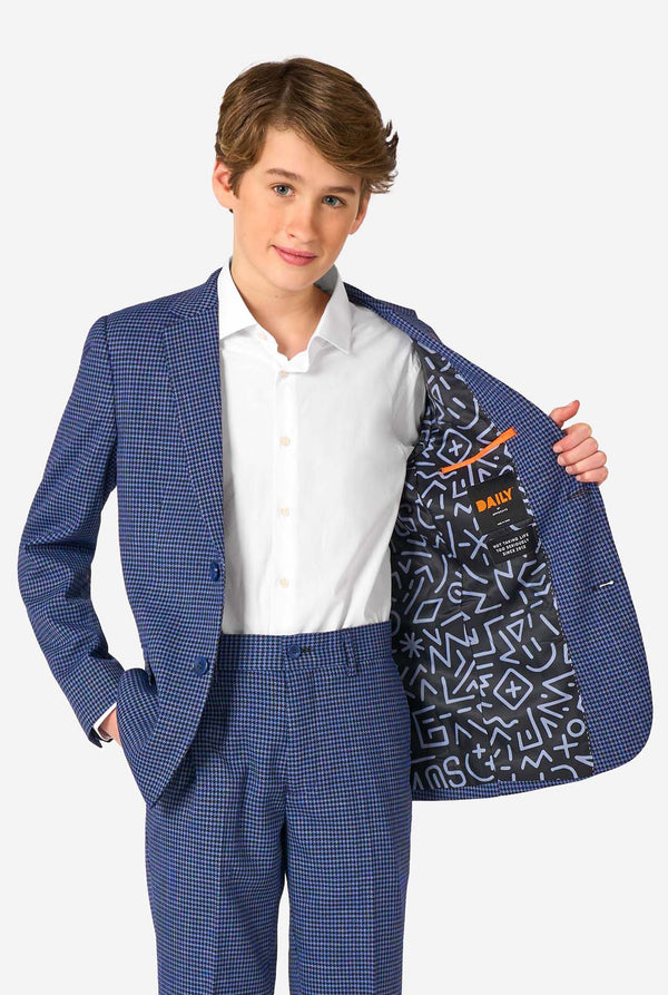 A teen boy wearing a navy and blue checkered suit with a white dress shirt. The suit has a modern fit with two buttons and flap pockets. He stands against a plain white background. Holding his jacket open