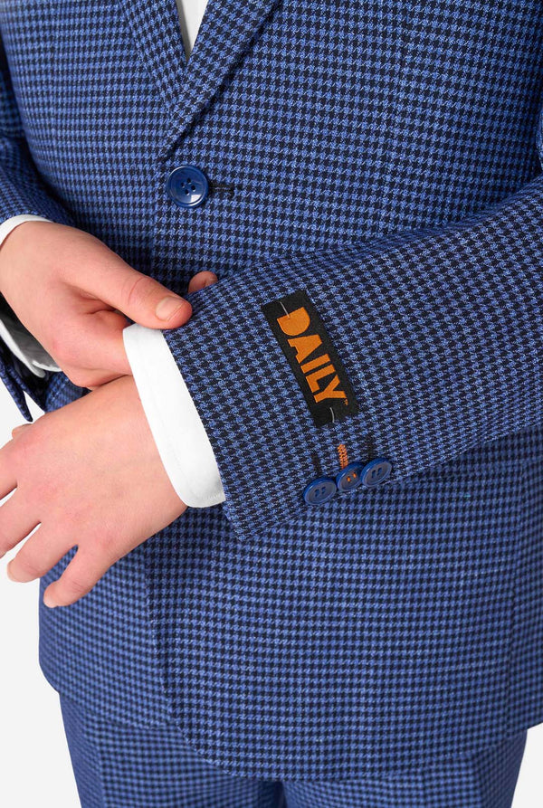 A teen boy wearing a navy and blue checkered suit with a white dress shirt. The suit has a modern fit with two buttons and flap pockets. He stands against a plain white background. Close up of the sleeves