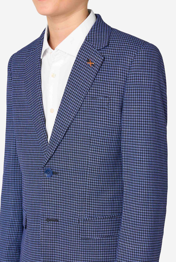 A teen boy wearing a navy and blue checkered suit with a white dress shirt. The suit has a modern fit with two buttons and flap pockets. He stands against a plain white background. Close up of the chest