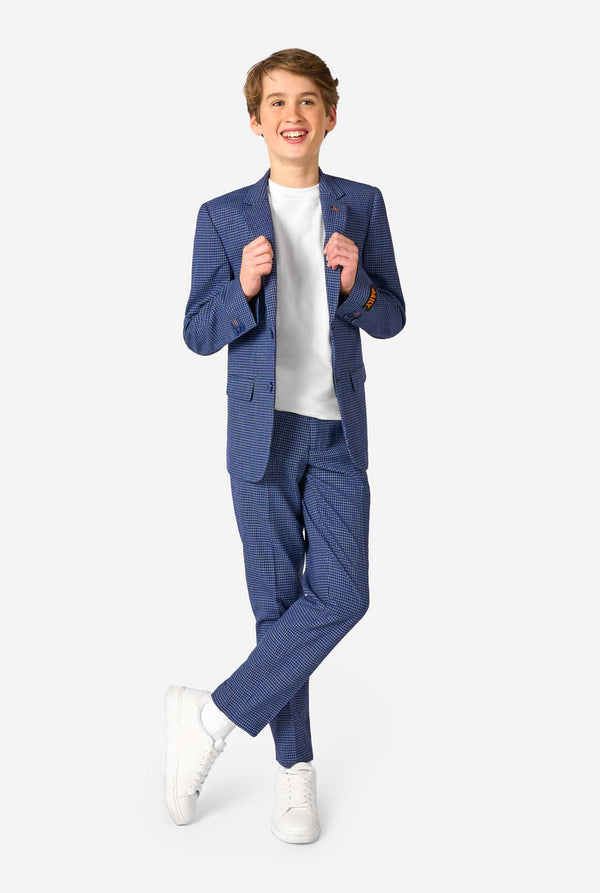 A teen boy wearing a navy and blue checkered suit with a white dress shirt. The suit has a modern fit with two buttons and flap pockets. He stands against a plain white background. Full body image