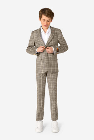 A teen boy wearing a tan checkered suit with a white dress shirt. The suit has a modern fit with two buttons and flap pockets. He stands against a plain white background. Full body image