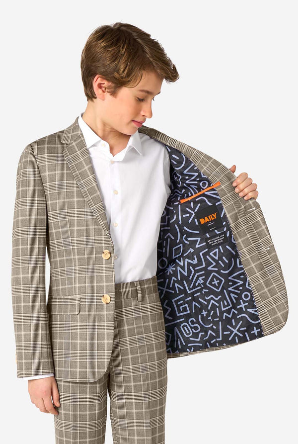 A teen boy wearing a tan checkered suit with a white dress shirt. The suit has a modern fit with two buttons and flap pockets. He stands against a plain white background. Holding his jacket open