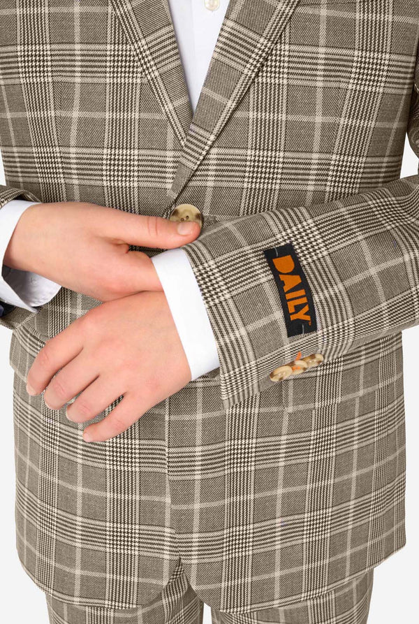 A teen boy wearing a tan checkered suit with a white dress shirt. The suit has a modern fit with two buttons and flap pockets. He stands against a plain white background. Close up of the sleeves