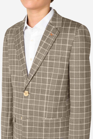 A teen boy wearing a tan checkered suit with a white dress shirt. The suit has a modern fit with two buttons and flap pockets. He stands against a plain white background. Close up of the chest