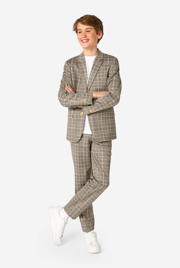 A teen boy wearing a tan checkered suit with a white dress shirt. The suit has a modern fit with two buttons and flap pockets. He stands against a plain white background. Full body image