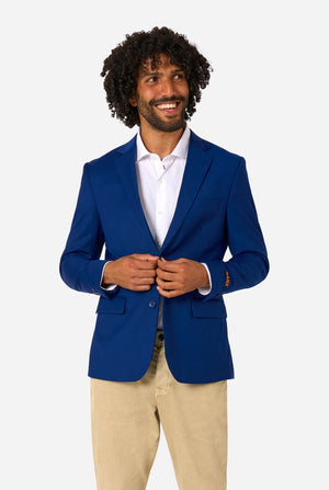 Man wearing a blue blazer over a white shirt with beige pants on a white background