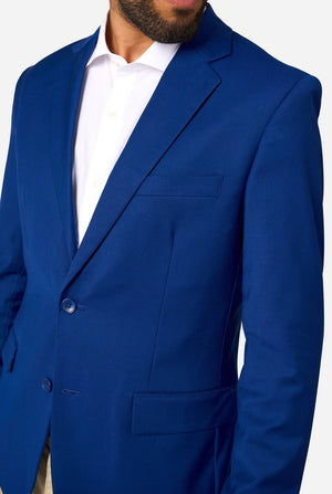 Person wearing a blue blazer and beige pants on a white background, chest close-up.