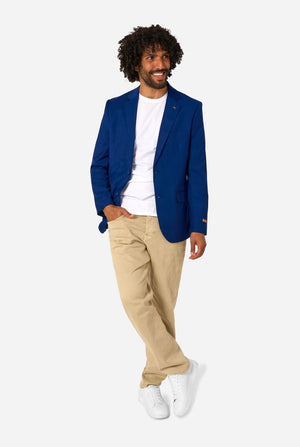Man wearing a blue blazer, white shirt, beige pants, and white sneakers on a white background