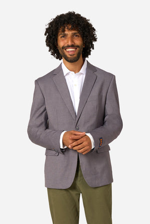 Man wearing a gray blazer over a white shirt with green pants on a white background