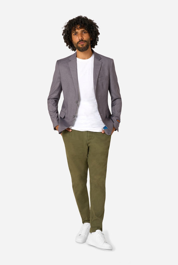 Man wearing a gray blazer, white shirt, green pants, and white shoes on a white background