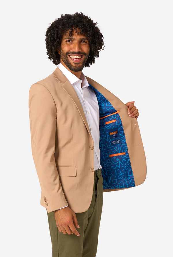 Man wearing a beige blazer with a colorful lining, standing against a white background