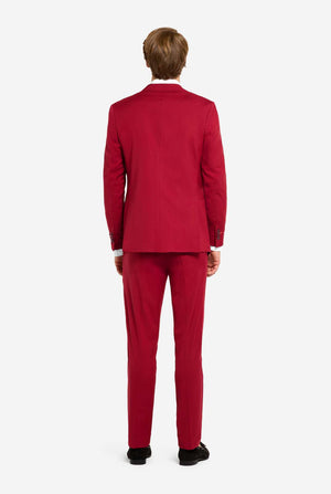 Image with light grey background and man wearing Bright Burgundy men’s suit and white shirt. Suits consists of blazer and pants. View from the back.