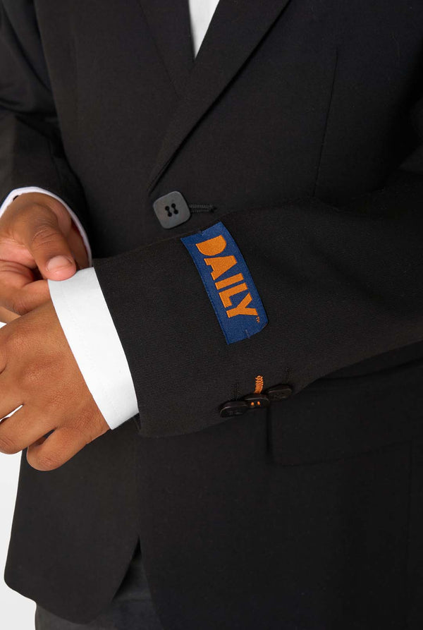 Close-up of a blazer sleeve with a blue and orange “DAILY” label and orange stitching near the buttons.