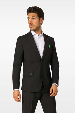 A man wearing a black blazer, white shirt, and black trousers, looking to the side with a neutral expression.