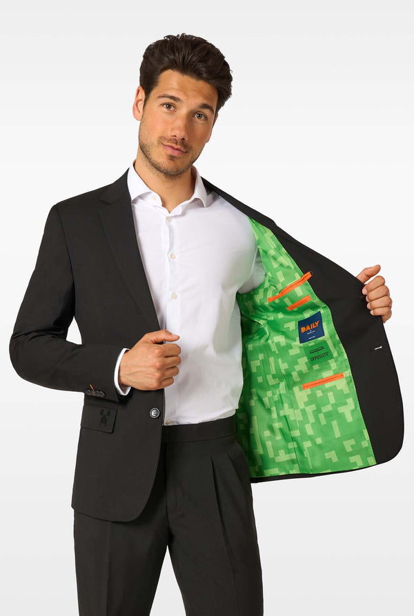 A man in a black blazer showing the inside lining printed with green pixelated Minecraft-style graphics.