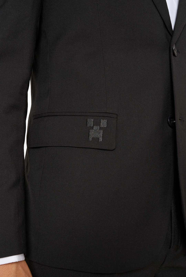 Close-up of a blazer pocket embroidered with a small black pixelated design inspired by Minecraft.
