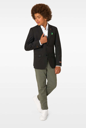 Full-body view of a child in a black blazer, white shirt, olive trousers, and white sneakers, looking down.