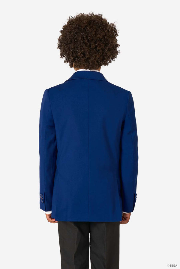 Back view of a boy wearing a blue blazer and black trousers against a white background.