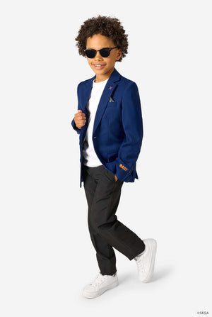 A boy walking confidently in a blue blazer, white T-shirt, black trousers, and white sneakers, wearing sunglasses.