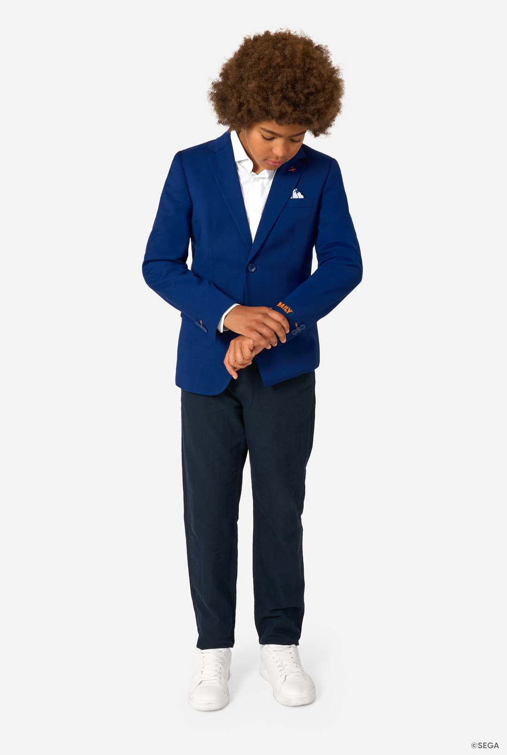 A child smiling while wearing a bright blue blazer, white shirt, and dark trousers, buttoning the jacket.