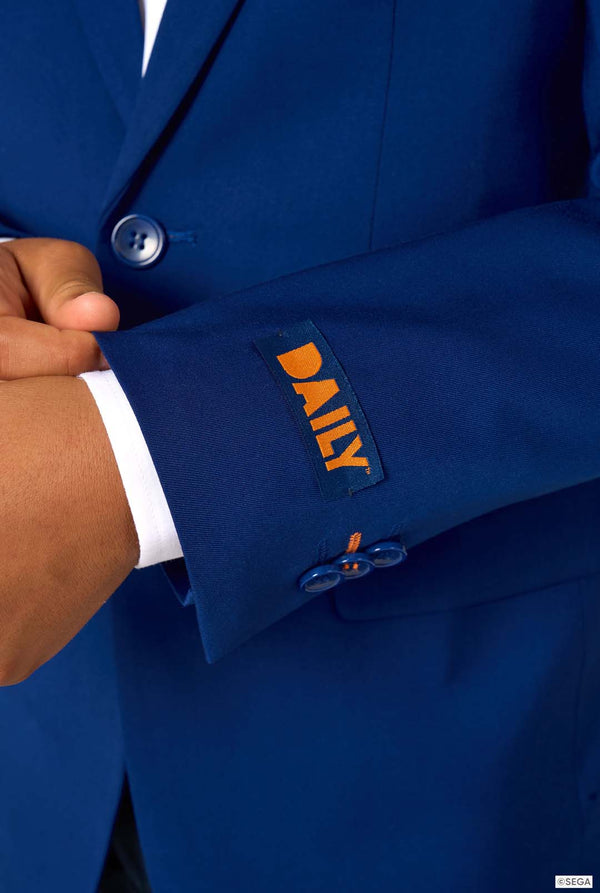 Close-up of the blazer sleeve with an orange label reading “DAILY” above two blue buttons.