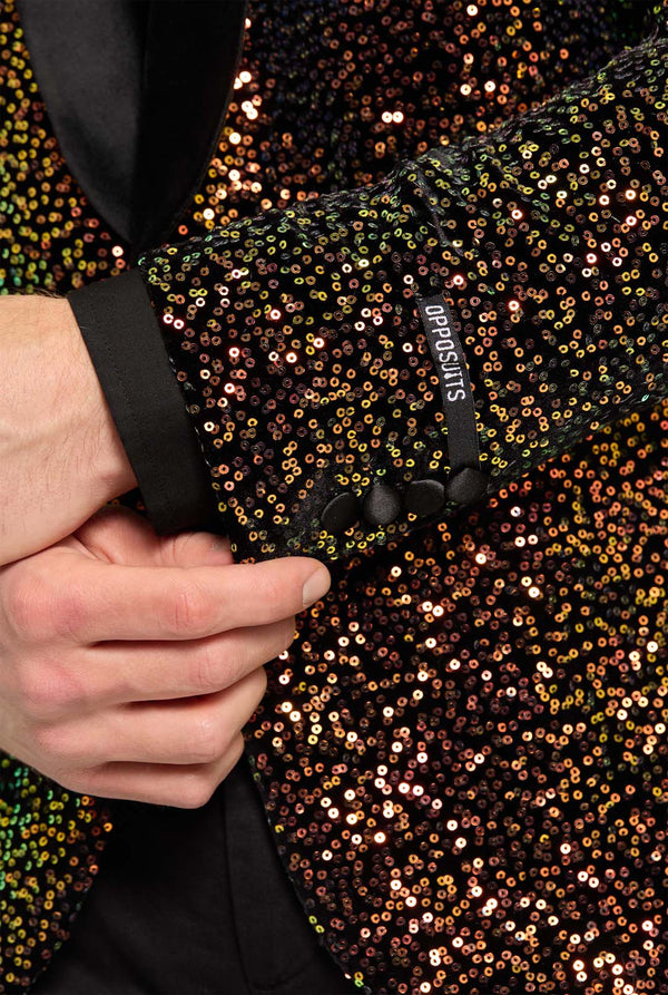 This image showcases a stylish men’s dinner jacket from OppoSuits Deluxe collection, featuring dazzling amber sequins that create a shimmering effect. The blazer has a sleek satin lapel, a tailored fit. The model pairs it with a classic black dress shirt and bow tie, making this jacket perfect for formal events, holiday parties, or New Year celebrations. Ideal for men who want to stand out with bold, luxurious, and festive attire. Sleeve Close up.