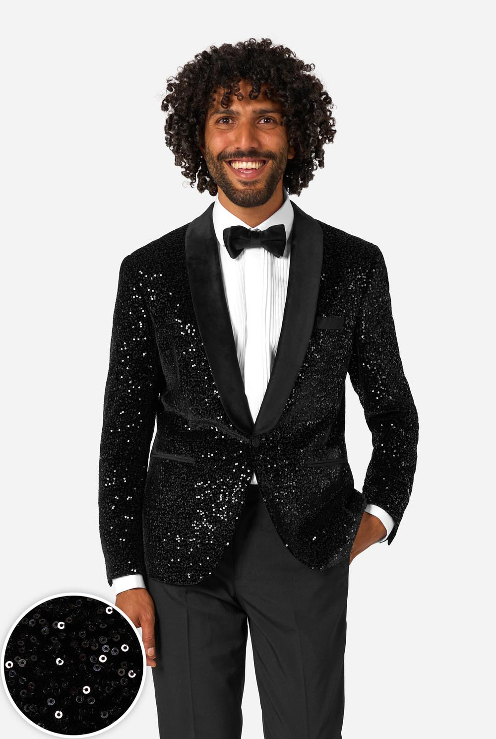 A man poses in a black sequined blazer or dinner jacket, wearing a solid white shirt underneath. Close up circle in the left corner.