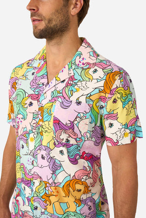 Man wearing a colorful Hawaiian shirt with My Little Pony character pattern on a light background. Chest close-up.