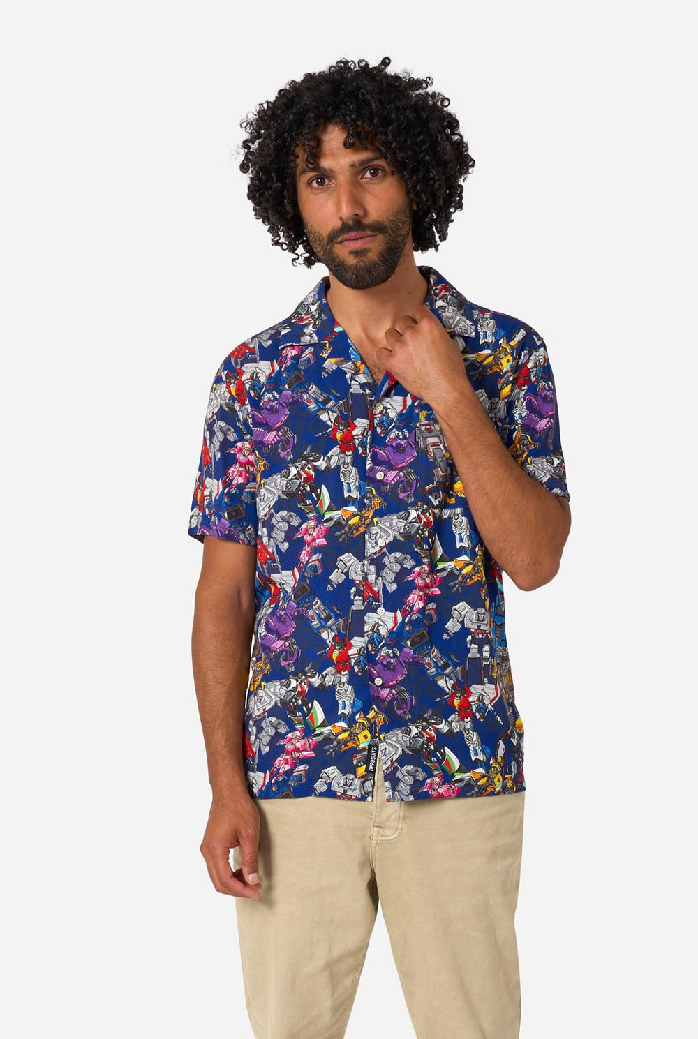 Man wearing a colorful patterned Transformer shirt on a light background