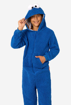 A kid is wearing a blue sesame street onesie resembling Cookie Monster. 
