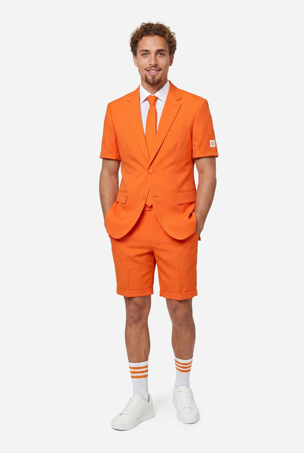 Man wearing an orange summer suit with matching tie on a light background. Full body image.