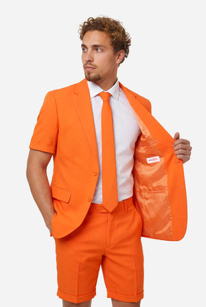 Man wearing an orange summer suit with matching tie on a light background. Holding one side of the jacket open.