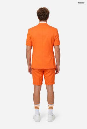 A man modeling a bright orange short-sleeve suit consisting of a blazer and matching shorts, paired with a white dress shirt and orange tie, against a light gray background. View from the back.