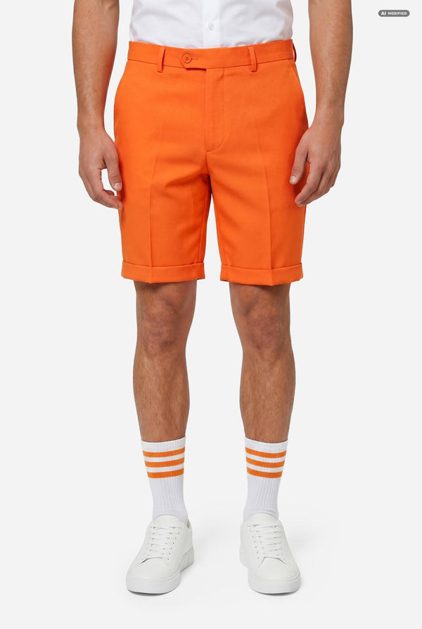 A man modeling a bright orange shorts, paired with a white dress shirt and orange tie, against a light gray background.