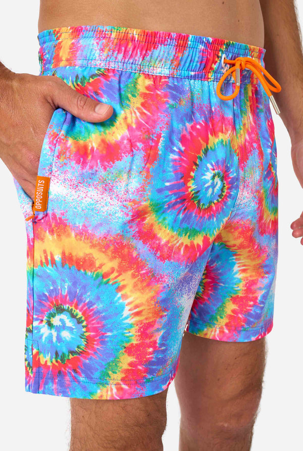 Man wearing a men's rainbow tie-dye swim shorts with a bold, colorful spiral pattern. A fun and trendy choice for beach days and pool parties. Close up front.